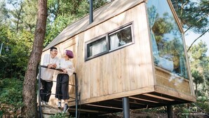 A wooden treehouse with a single window and a chimney, situated in a forested area. - U Lesa Retreat Nha Ben Rung (Hanoi)