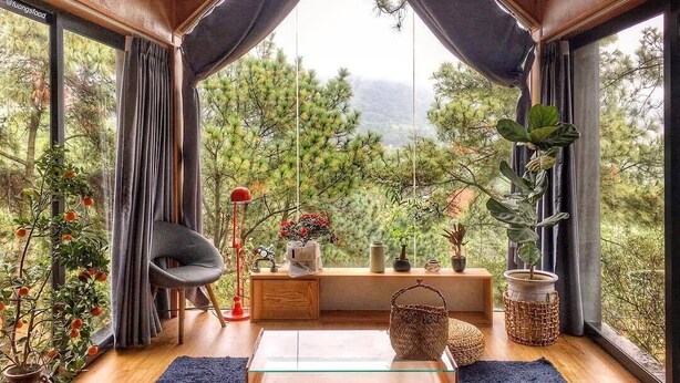 A cozy room with a large window, a wooden ceiling, and a glass coffee table. - U Lesa Retreat Nha Ben Rung (Hanoi)