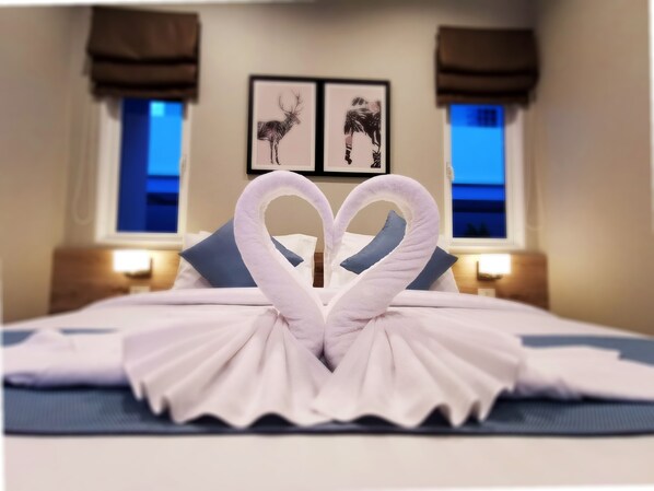 Een hotelkamer met een bed, versierd met handdoeken in de vorm van een hart.