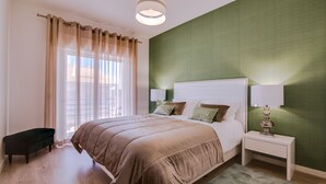 A bedroom with a bed, bedside tables, a bench, and a window with curtains.