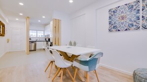 A modern kitchen with white cabinets, a wooden dining table, and white chairs.