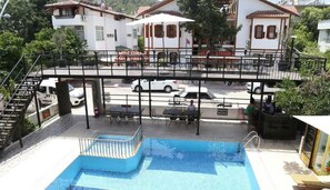 A swimming pool with a sun deck, outdoor seating, and a pedestrian bridge. - Derin Luxury Hotel (Kemer)