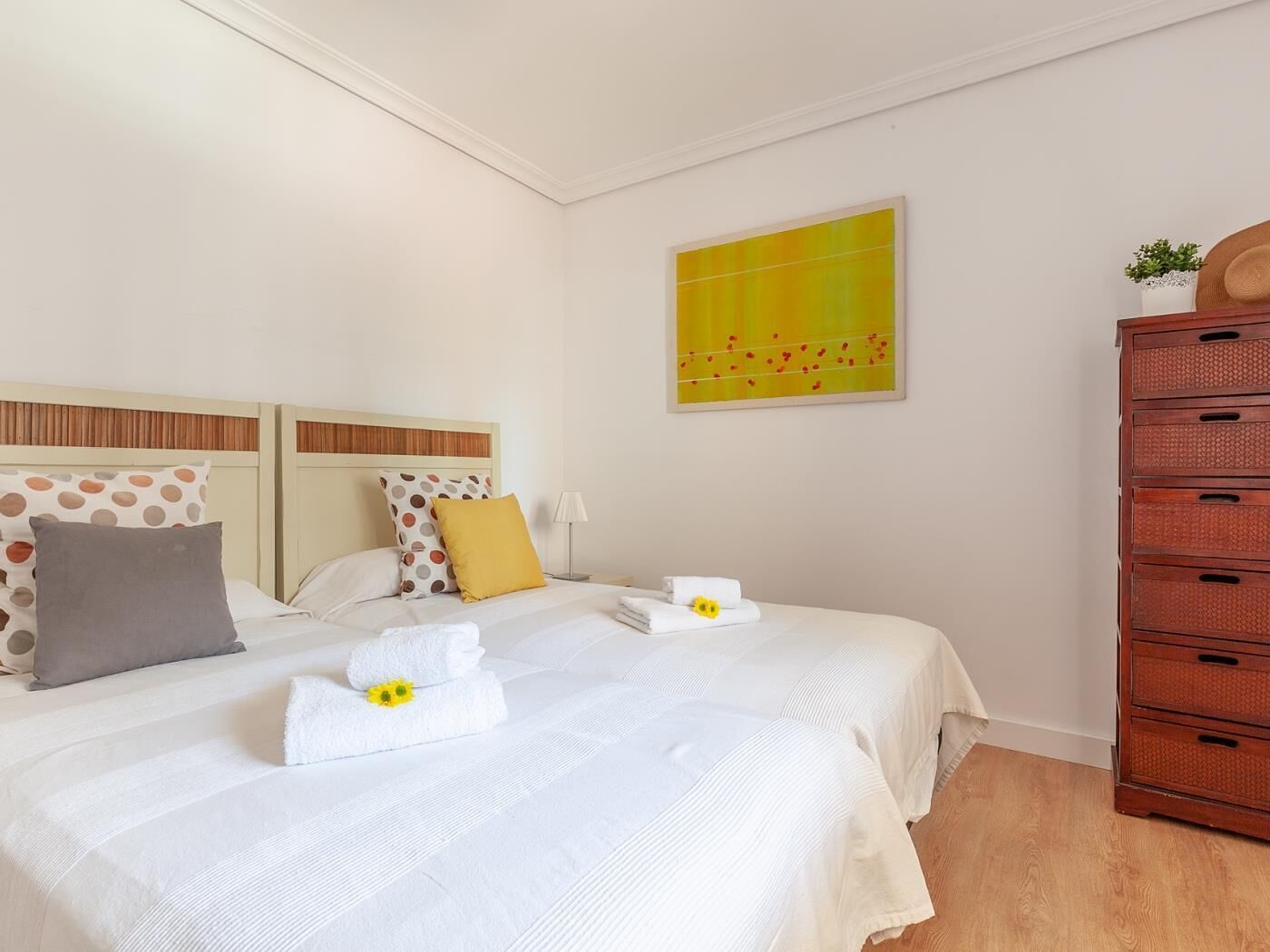 Een hotelkamer met twee bedden, een houten dressoir en een schilderij aan de muur.