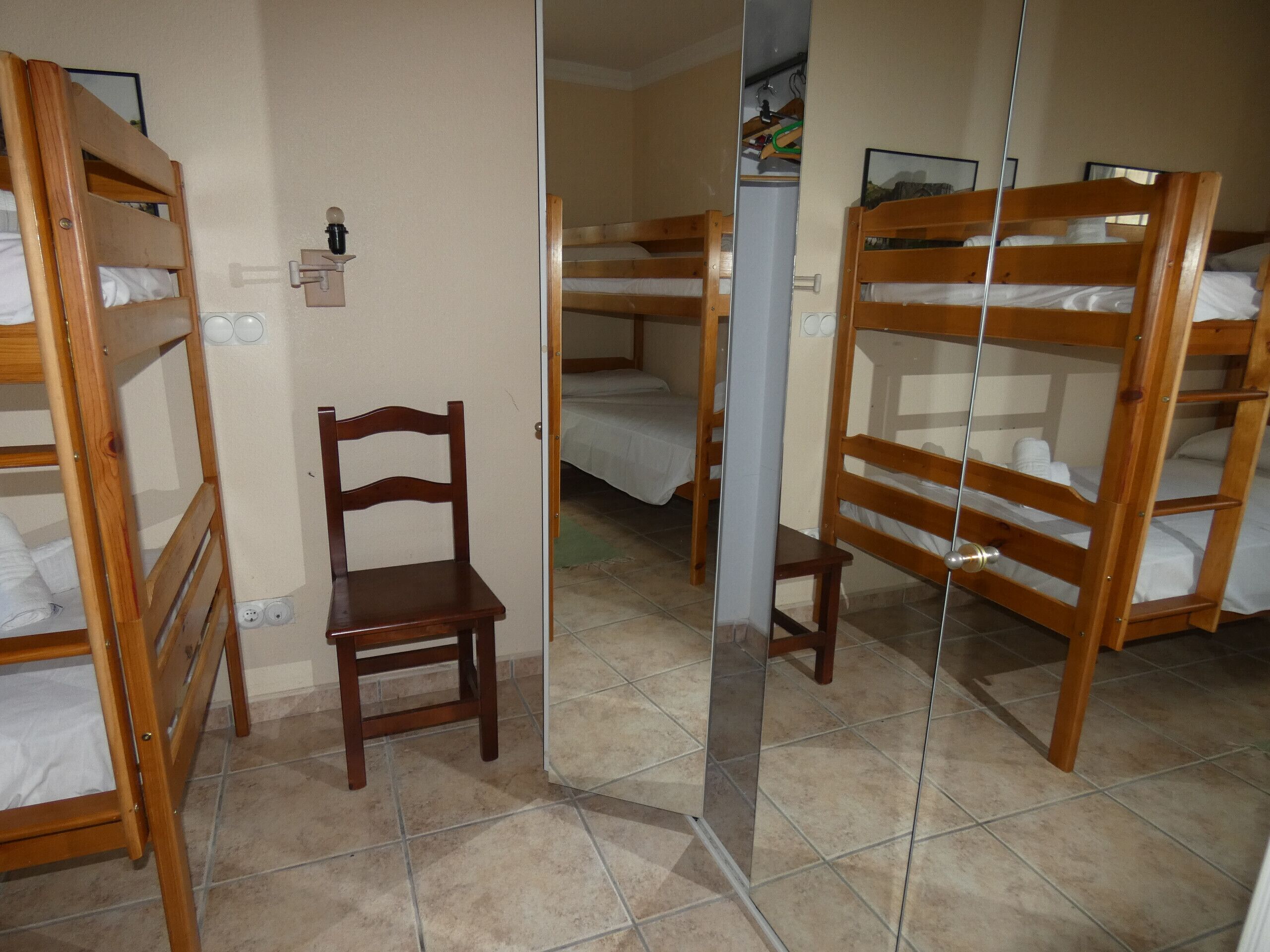 Una habitación con literas y una silla de madera.
