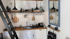 A compact kitchen with a wooden countertop, white cabinets, and a black ladder.