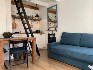 A compact living space with a kitchen area, a dining table with chairs, and a blue sofa. - Cosy "Pelican Dune",  minutes away from the beach. (Noordwijk aan Zee)