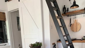 A dining area with a wooden table and chairs, a black metal ladder, and a white door.