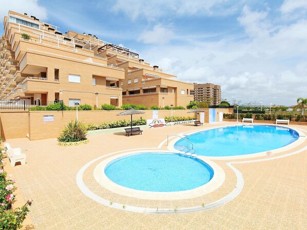 A hotel with two swimming pools, outdoor seating, and a landscaped garden. - Beautiful apartment for 6 guests with pool, A/C, TV and terrace (Orpesa Oropesa Del Mar)