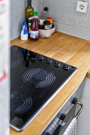 Een keuken met een zwart fornuis, een houten aanrecht en verschillende keukenspullen.