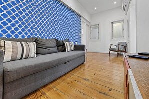 A modern living room with a grey sofa, wooden flooring, and a blue patterned wall. - Camões Cool Loft, at Chiado (Lisbon)