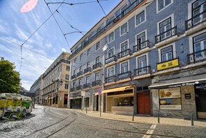 A street with tram tracks, buildings with balconies, and storefronts. - Camões Cool Loft, at Chiado (Lisbon)