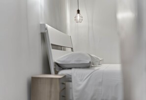 A minimalist bedroom with a bed, a bedside table, and a hanging light fixture.
