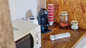 Een keukentafel met een magnetron, koffiezetapparaat en een rol keukenpapier.