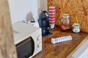 Eine Küchenarbeitsplatte mit einer Mikrowelle, einer Kaffeemaschine und einer Küchenpapierrolle.