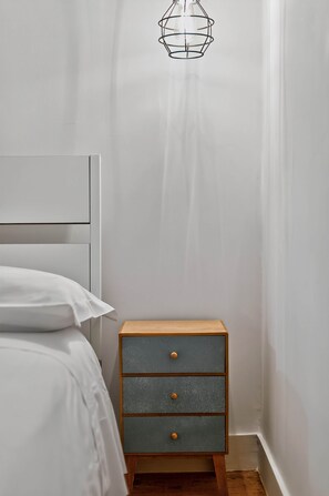 Ein Schlafzimmer mit einem Bett, einem Nachttisch mit Schubladen und einer Hängelampe.