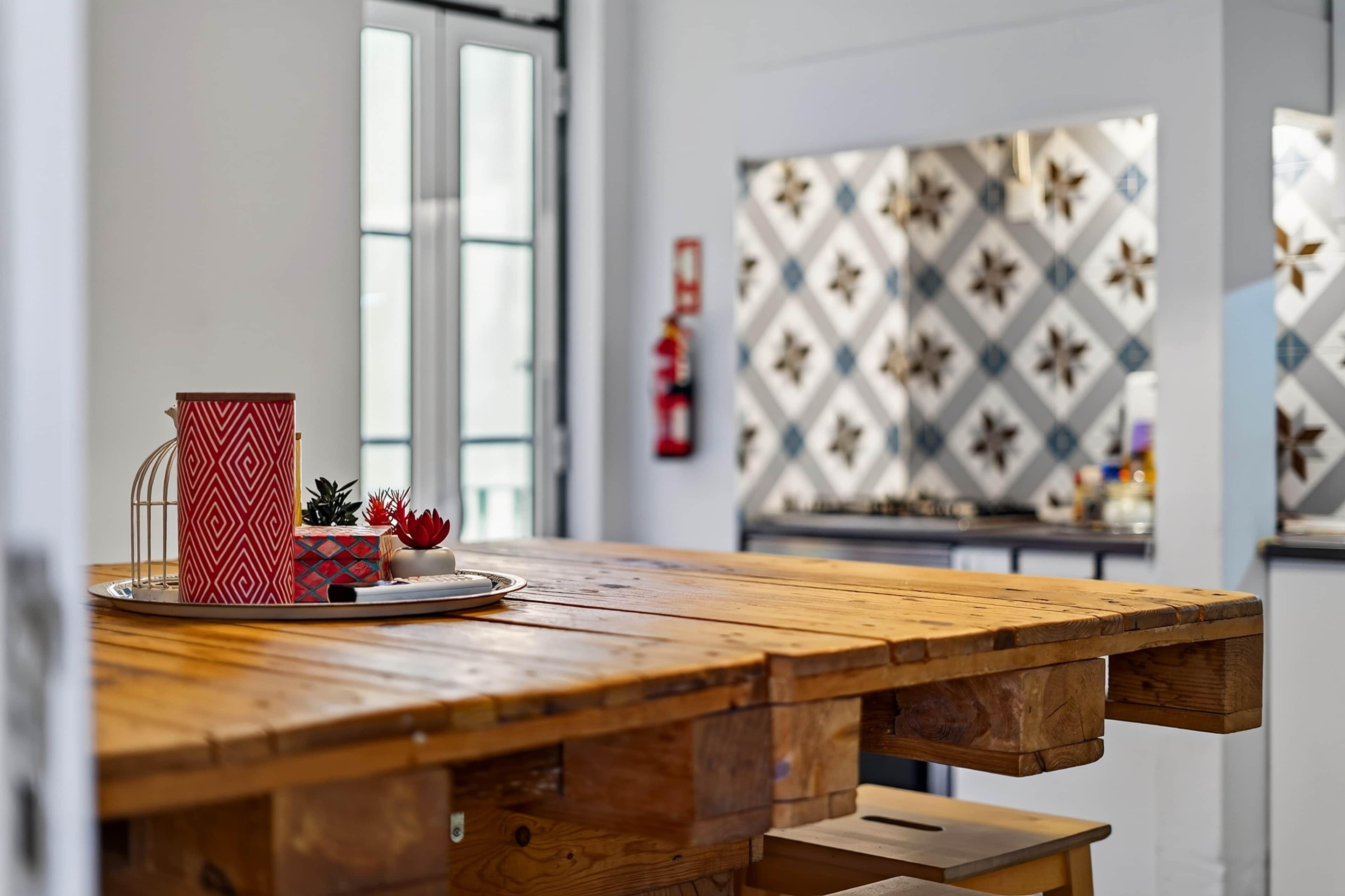 A wooden table with a tray, a red patterned container, and decorative items.