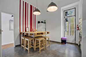 Een moderne keuken met een houten tafel en stoelen, een muur met rode en witte strepen, en hangende lampen.