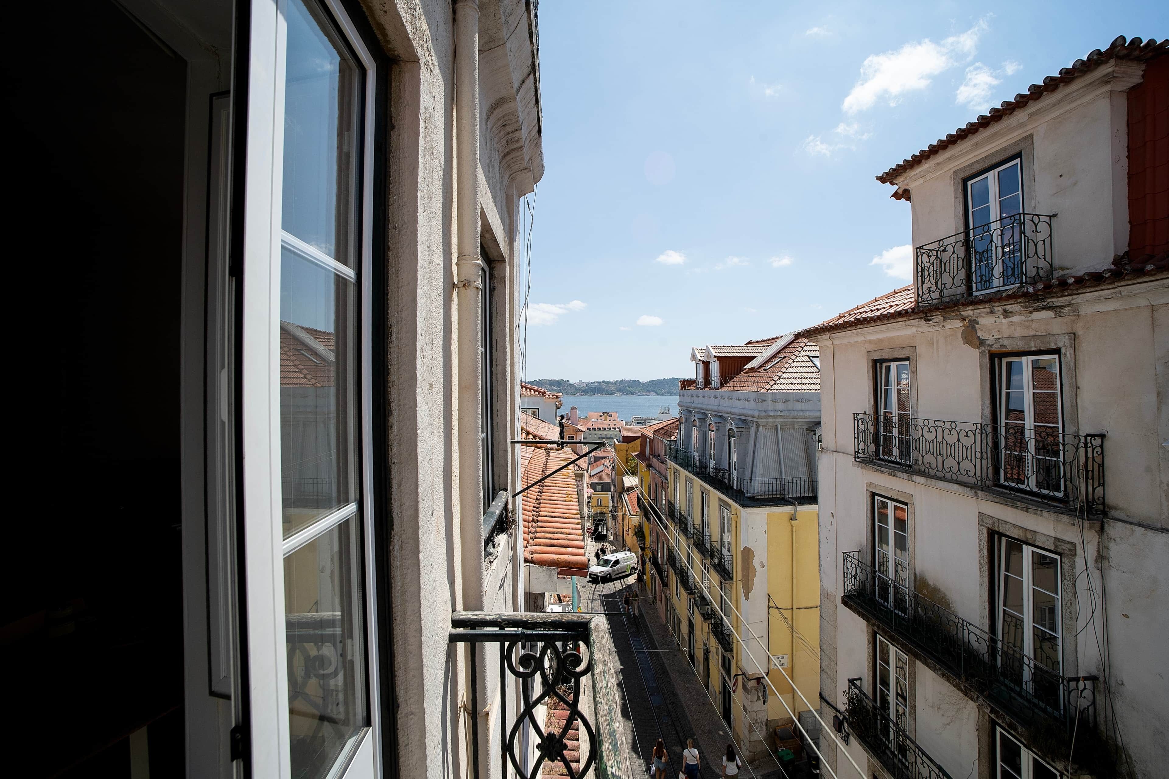 Una calle estrecha flanqueada por edificios, cielo despejado y una vista distante del mar.