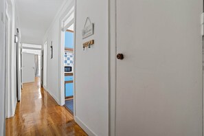 A hallway with wooden flooring, white walls, and a door with a keyhole.