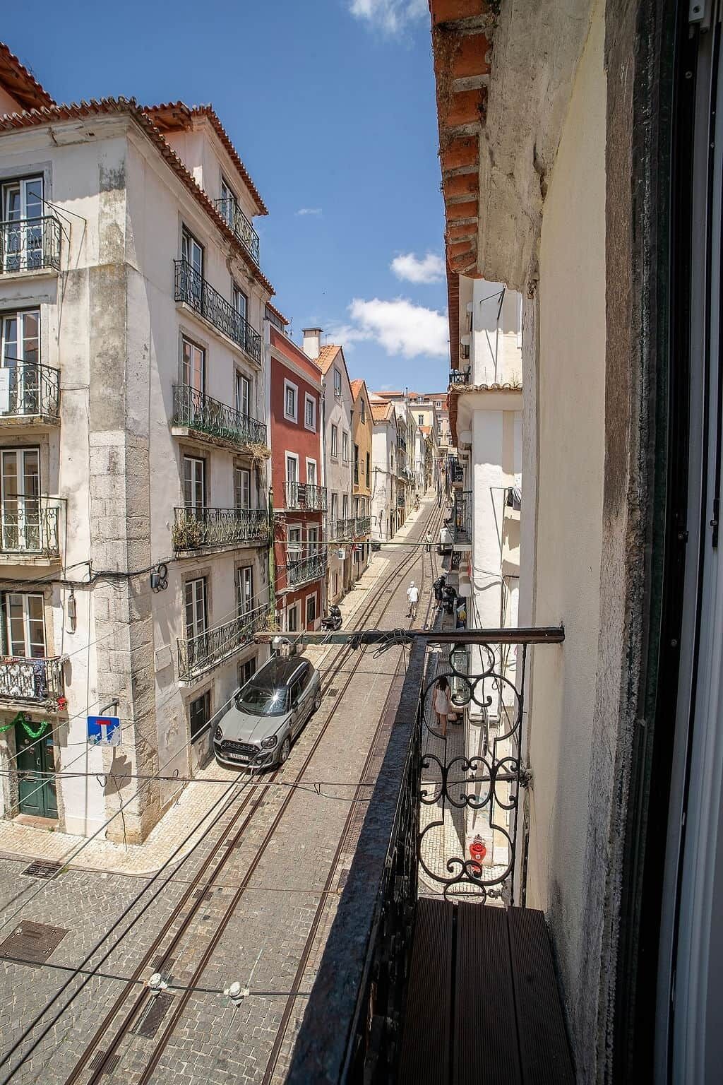 Une vue de rue avec des immeubles, un tramway et une voiture garée.