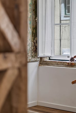 A room corner with a window, a wooden floor, and a wall with peeling paint.