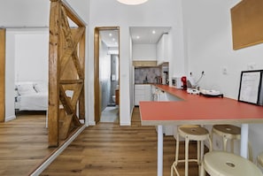 A modern kitchen with a red countertop, white cabinets, and a wooden door.