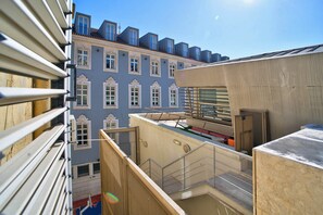 A multi-story building with balconies, a sports court, and a view of adjacent buildings. - Saint Paul, Third Floor (Lisboa)