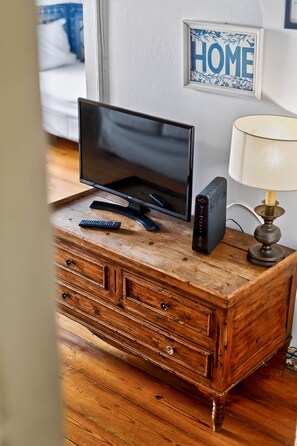 A wooden dresser with a television, remote control, and a speaker on top.