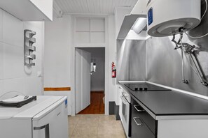 A modern kitchen with stainless steel appliances, a coffee machine, and a fire extinguisher mounted on the wall. - Lively Bairro Alto, in the heart of the nightlife district (Lisboa)
