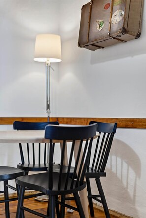 Ein Essbereich mit Tisch, Stühlen, einer Lampe und einem Wandkorb.
