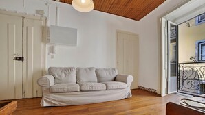 Una habitación con piso de madera, un sofá color beige y un techo blanco.
