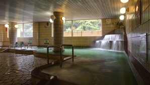 Un espace de bien-être comprenant un jacuzzi, une petite cascade décorative et des murs recouverts de carreaux.