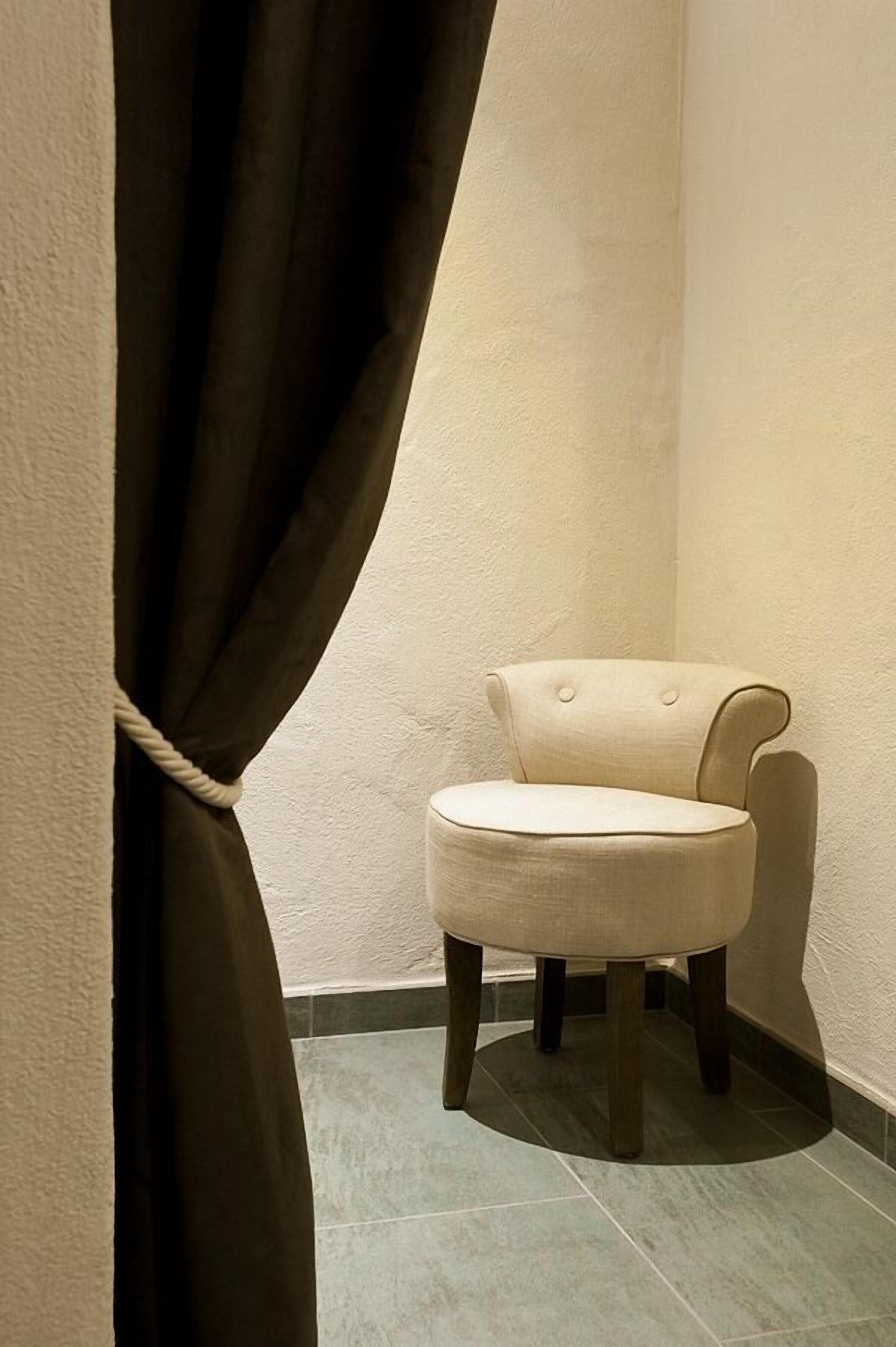 A corner room with a chair and a curtain.
