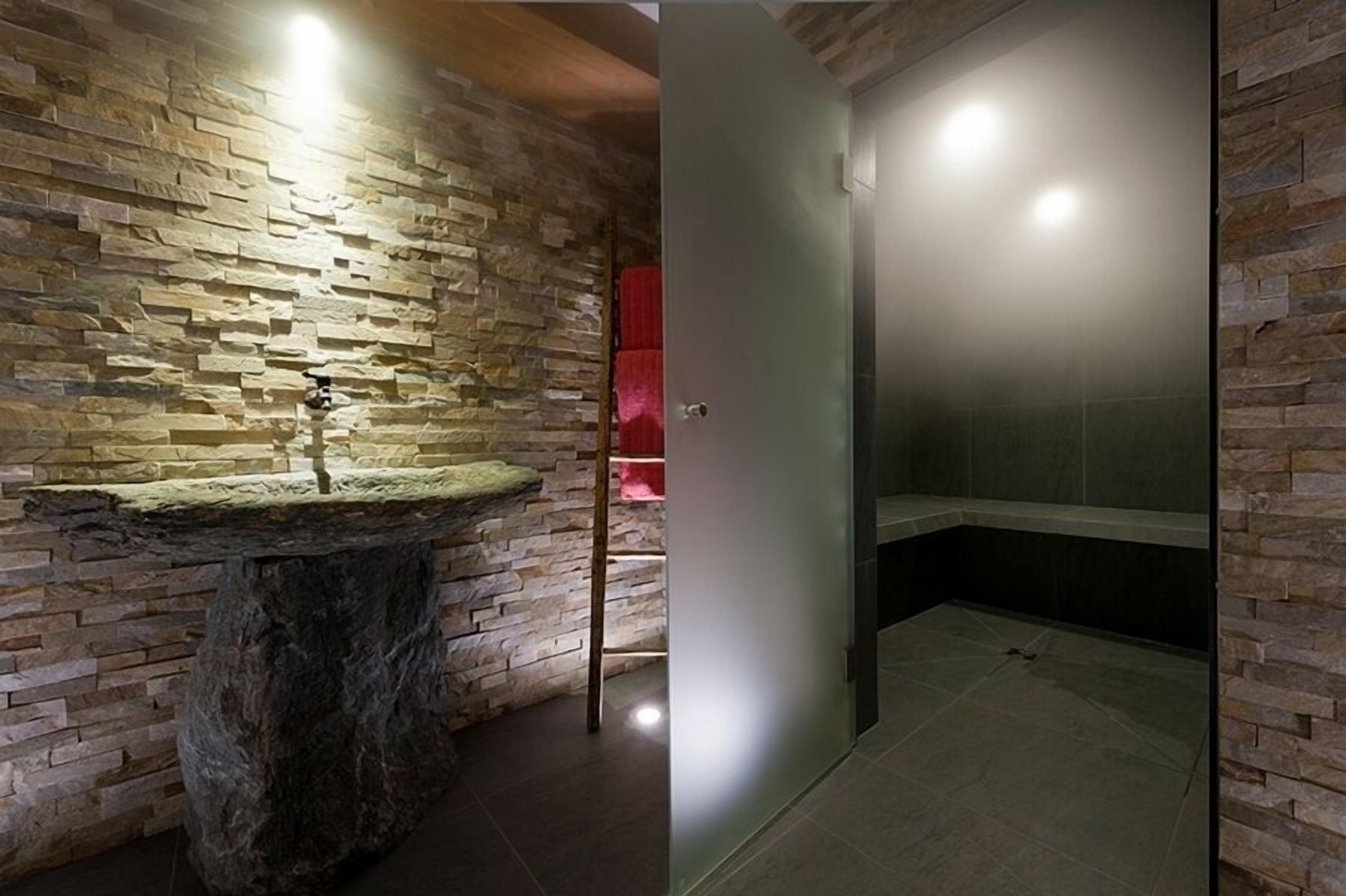 A bathroom with a stone wall and a sink.