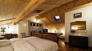 A bedroom with a wooden ceiling, a skylight, a bed, a dresser, and a desk with a chair. - La Vallée Hotel & Spa (Bagnes)