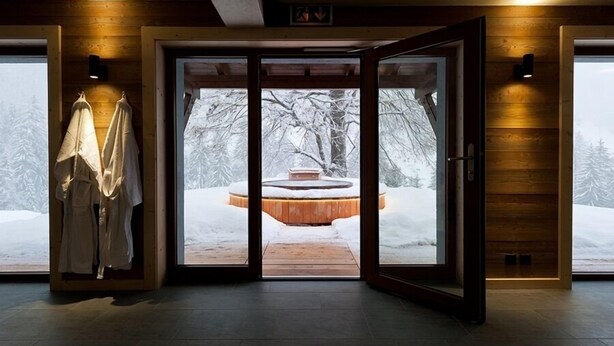 A wooden interior with a glass door leading to a snowy outdoor area. - La Vallée Hotel & Spa (Bagnes)