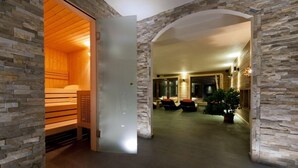 A modern interior with a sauna, stone walls, and a seating area with a potted plant. - La Vallée Hotel & Spa (Bagnes)