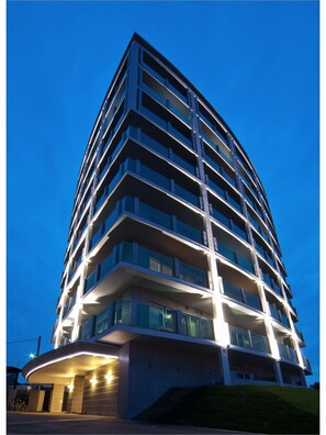 A modern multi-story hotel with a curved facade, large windows, and a well-lit entrance. - Herber Light SHINONOME (Otaru)