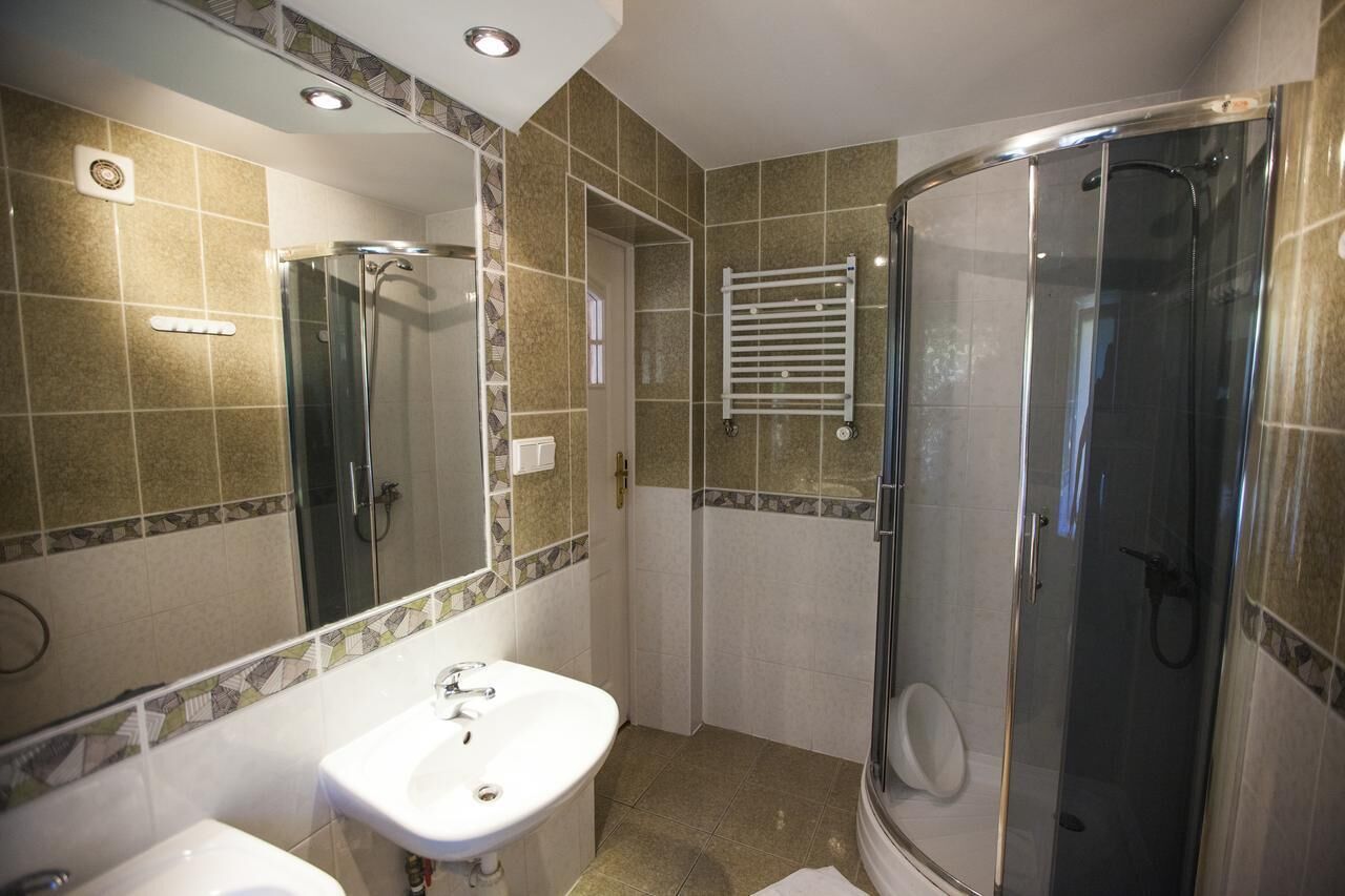 A bathroom with a glass-enclosed shower, a sink, and a mirror.