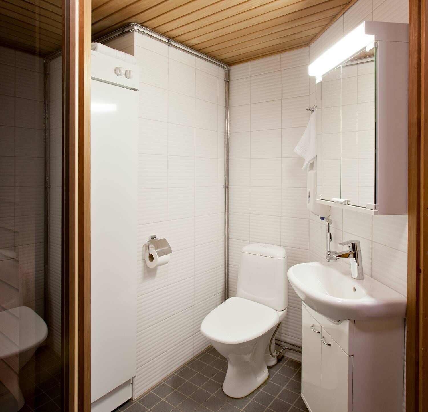 A compact bathroom with a toilet, a sink, and a mirror.