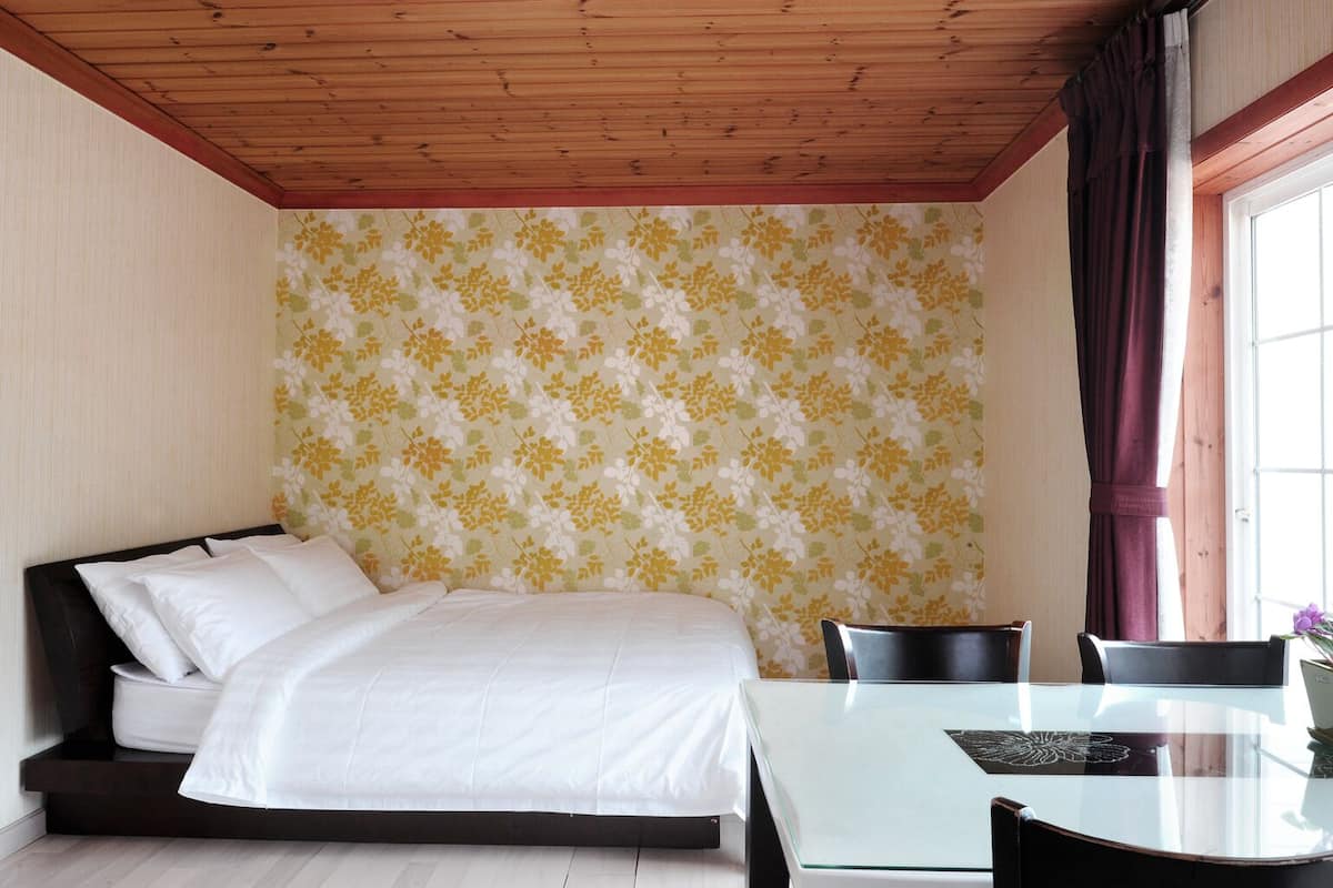 Un dormitorio con cama, una mesa de vidrio y una silla.