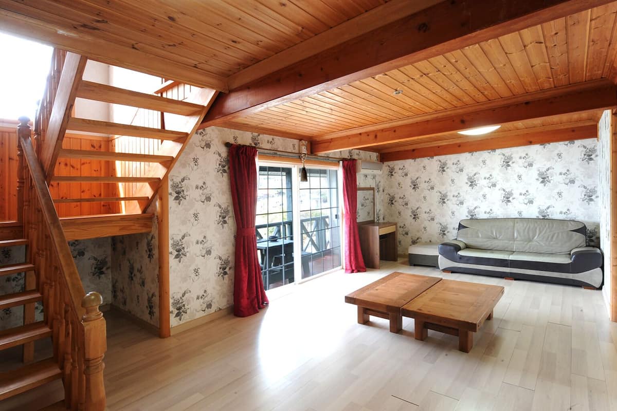 Un interior de madera con una escalera, un sofá y una mesa de madera.