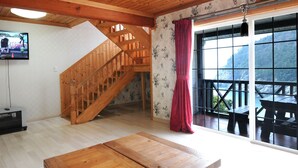 Un intérieur en bois avec un escalier, un t éléviseur et une vue dégagée grâce à de grandes fenêtres.