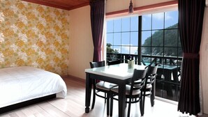 Une chambre à coucher avec un lit, une table à manger avec des chaises, une fenêtre avec des rideaux et une vue sur l’extérieur.