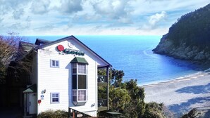 Un bâtiment blanc avec un toit vert et une enseigne sur laquelle on peut lire : « Flamingo’s Beach House ».