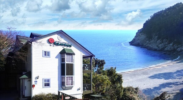 A white building with a green roof and a sign that reads "Flamingo's Beach House". - Geoje Floria Pension (Geoje)