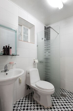 A bathroom with a white sink, toilet, and a glass-enclosed shower. - Geoje Floria Pension (Geoje)