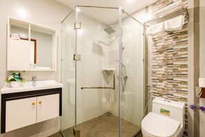 Enjoy a refreshing shower in the bathroom, featuring a glass-enclosed shower with a handheld showerhead and faucet.