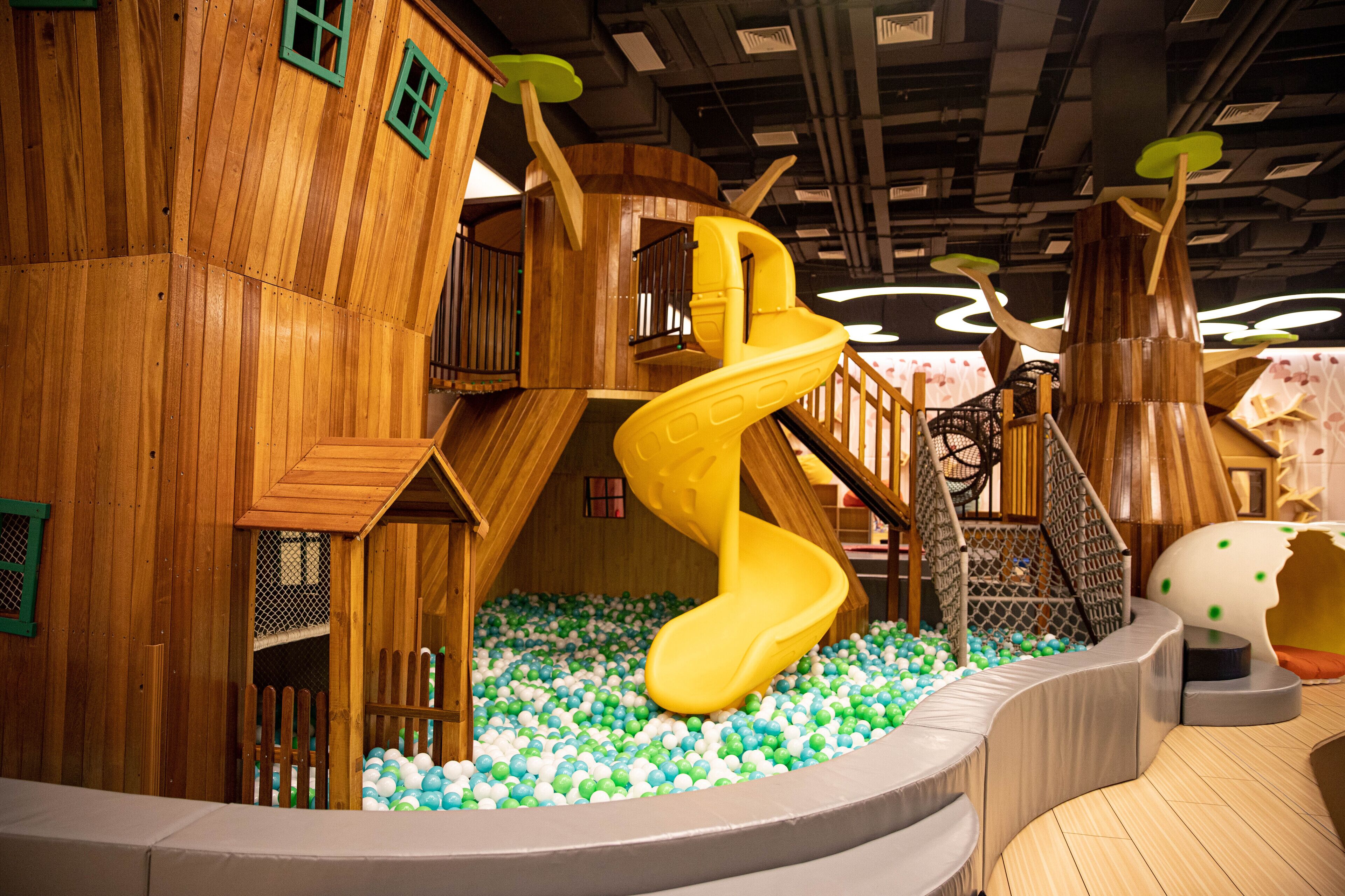 A wooden play structure with a spiral slide and ball pit.