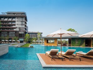 A modern hotel with a swimming pool, lounge chairs, and umbrellas. - Sunshine Yi Hotel Haitang Bay, Sanya (Sanya)